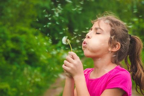 Premium Photo | Girl blowing dandelion flower in garden