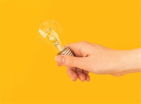 Premium Photo | Woman hand with led light bulb, led lamp on orange or yellow isolated background