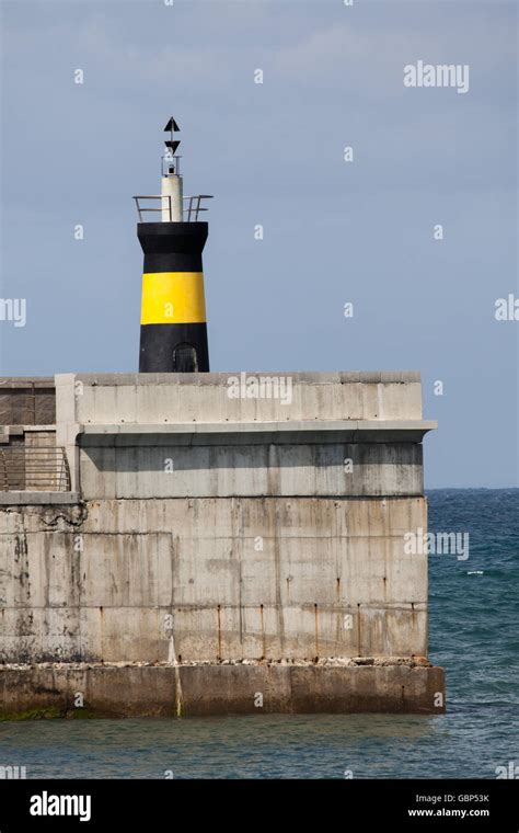 Lighthouse and harbour wall at Comillas Northern Spain Stock Photo - Alamy