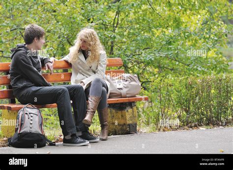 two young people sitting on bench in park and have a conversation Stock Photo - Alamy