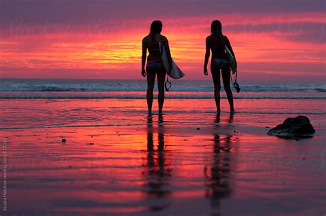 Surfer girls with surfboards looking at the sunset by Melchior van Nigtevecht - Stocksy United