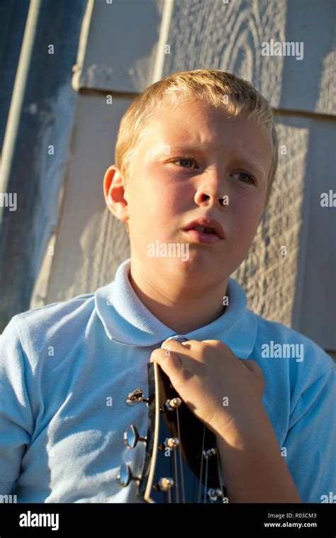 Thoughtful young boy holding a guitar Stock Photo - Alamy