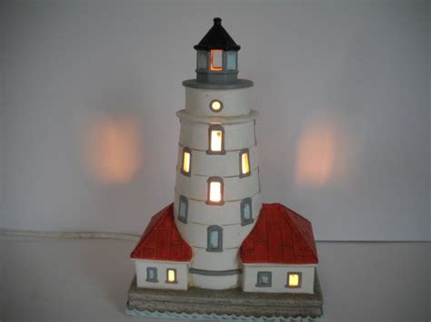 a white lighthouse with red roof and lights on