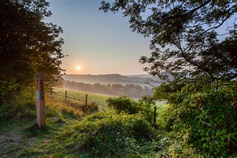 View from a high point over the green valley and countryside of the Cotswold landscape, with the ...