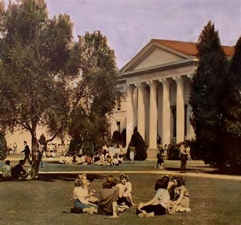 an old photo of people sitting on the grass in front of a building with columns