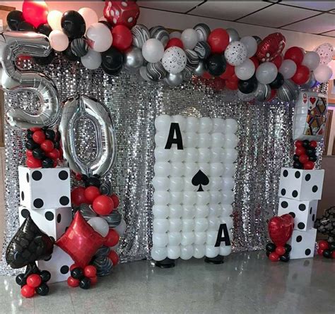 a casino themed party with balloons, dices and streamers in the shape of playing cards