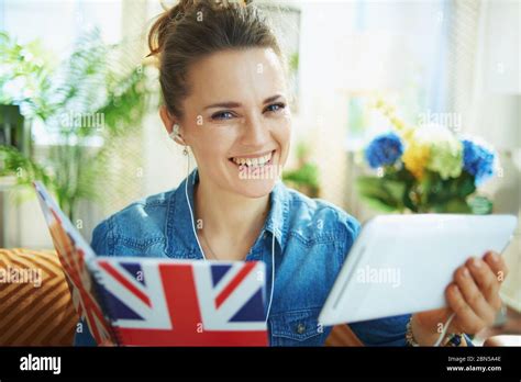 Portrait of happy stylish 40 years old housewife in jeans shirt with tablet PC and UK flag ...