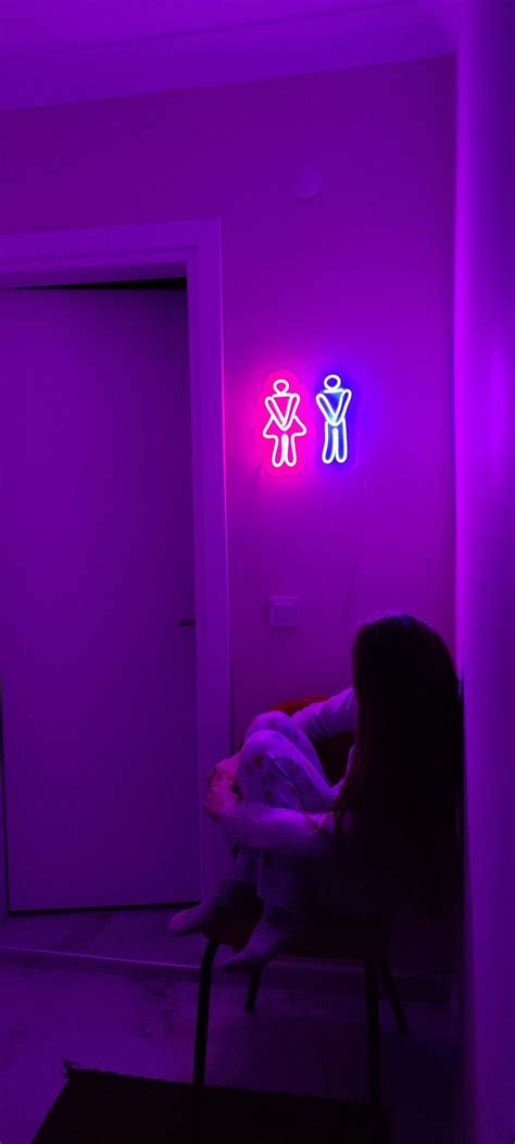 a woman sitting in a chair next to a door with neon lights on the wall