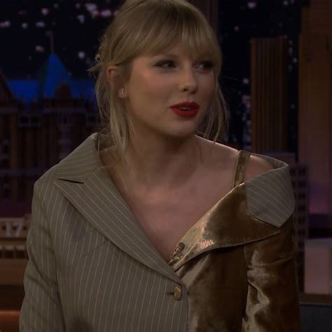 taylor swift on the tonight show wearing red lipstick and a brown jacket with gold stripes