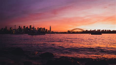 Download wallpaper 2560x1440 bridge, city, sunset, sea, waves widescreen 16:9 hd background