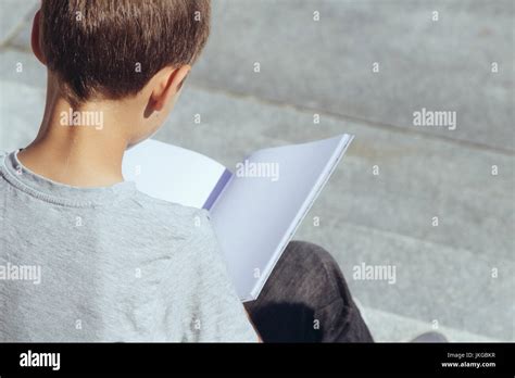 Young boy reading book outdoors Stock Photo - Alamy