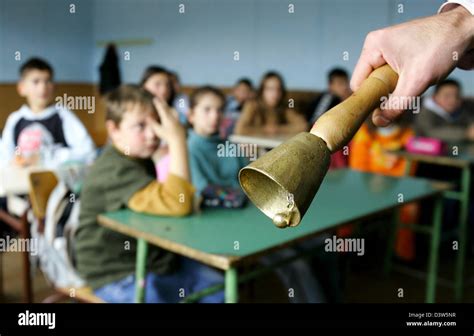 The picture shows a teacher's hand ringing the school bell in a classroom in Nebregoste ...