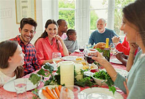 Multi-ethnic multi-generation family enjoying Christmas dinner at table ...