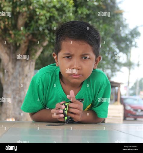 Portrait Of Boy Leaning On Retaining Wall Against Tree Stock Photo - Alamy