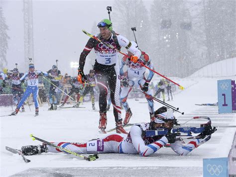 France’s Fourcade shoots as Austria’s Landertinger leaves the shooting range during the men’s ...