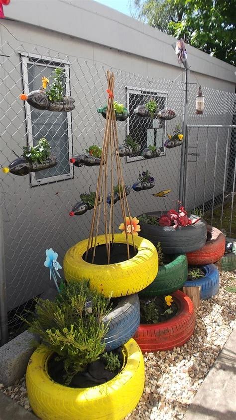 several tires stacked on top of each other in front of a fence with plants growing out of them