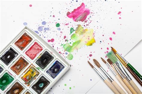 Premium Photo | Splashes of watercolor paint and painting supplies close up