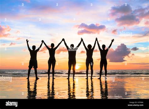 Silhouette of a group of people holding hands up on the beach with a Stock Photo: 125278726 - Alamy