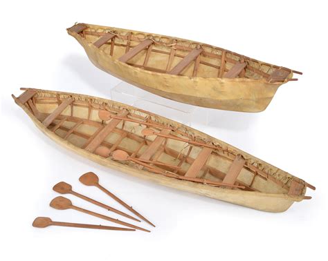 Two Inuit model Umiaks Greenland cedar and skin, with paddles, 64cm and 79cm long. (10) Provenanc