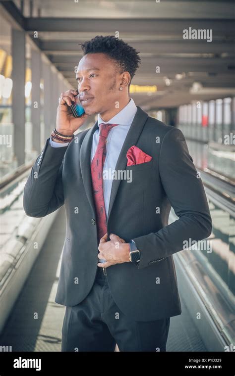 Close up of one young and attractive black businessman going to the airport wearing a black suit ...