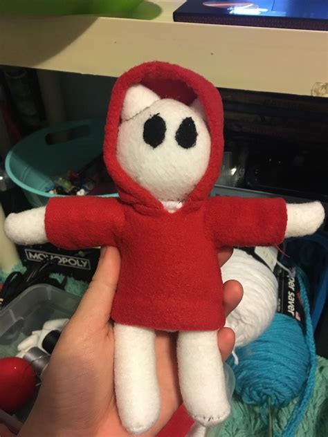 a person holding a stuffed animal in their hand and wearing a red hoodie with black eyes