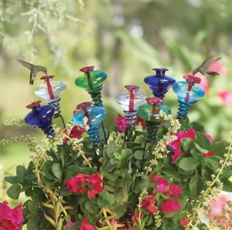 a vase filled with lots of colorful flowers and glass birds on top of each one