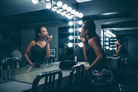 Black woman applying makeup in vanity mirror stock photo