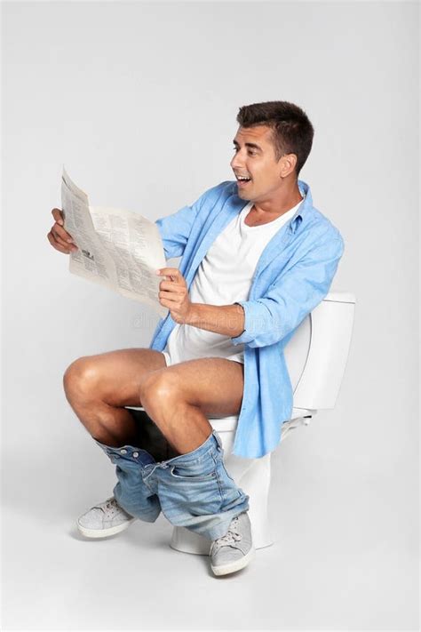 Young Man Reading Newspaper while Sitting on Toilet Stock Image - Image ...