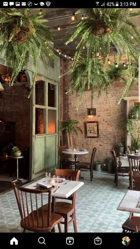 the interior of a restaurant with tables, chairs and potted plants hanging from the ceiling