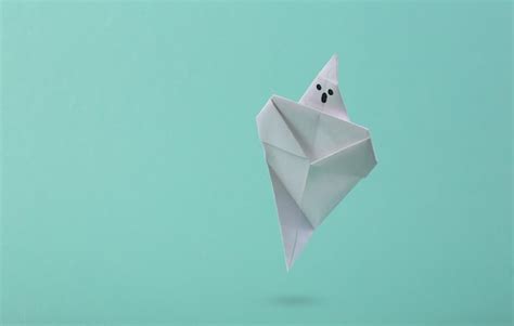 Premium Photo | Soaring origami ghost on a blue background creative halloween concept