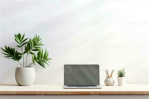 Minimalist simple office workspace with a laptop and a potted plant in soft natural light ...