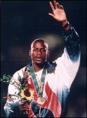 a man holding his hands up in the air while wearing a gold medal and ...