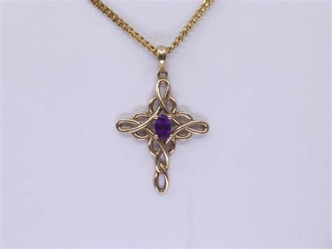 Lot - 9K GOLD CELTIC CROSS PENDANT SET WITH AMETHYST 1.1G WITH A QUALITY GOLD TONE DISPLAY CHAIN