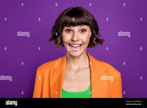 Photo of impressed sweet young woman dressed orange blazer smiling isolated purple color ...