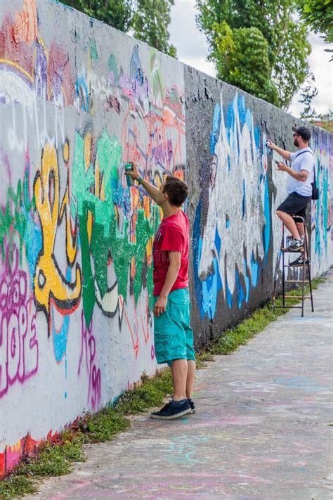 BERLIN, GERMANY - AUGUST 6, 2017: Graffiti Artists Painting on a Section of Berlin Wall in ...