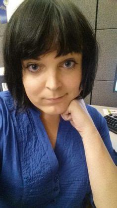 a woman sitting at a desk in front of a computer monitor with her hand on her chin