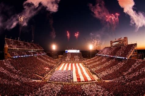 an american flag is on the field at a football game as fireworks go off in the background
