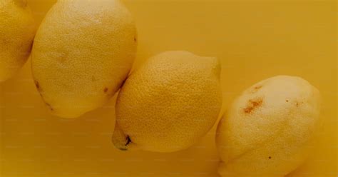 A group of lemons sitting on top of a yellow surface photo – Yellow ...