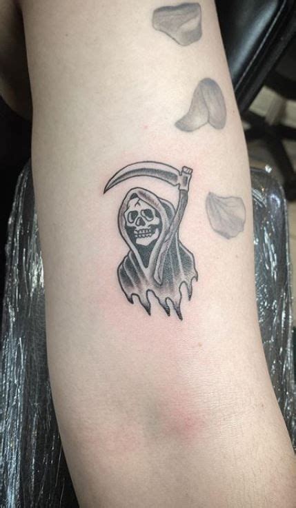 a person with a tattoo on their arm holding a knife and wearing a skull ...