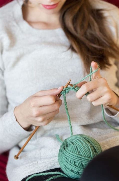 a woman is knitting yarn on the couch