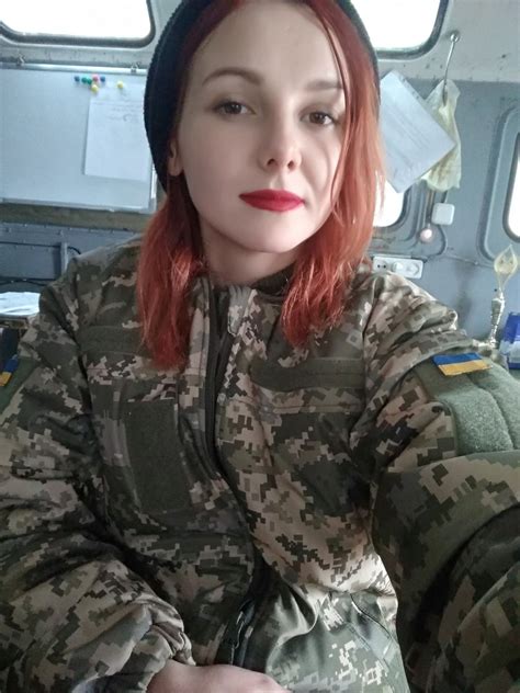 a woman with red hair wearing a camouflage jacket and beanie hat sitting in an airplane