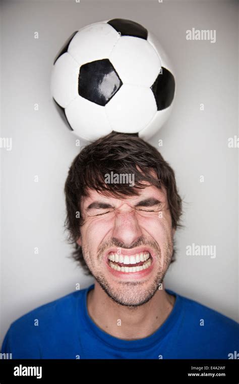 Young man balancing soccer ball on head Stock Photo - Alamy