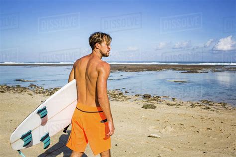 Back view of surfer with surfing board standing on sandy beach on summer day - Stock Photo ...