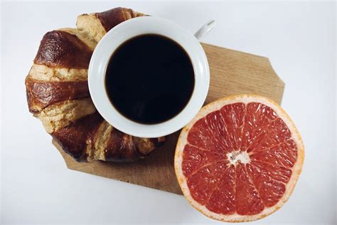Black Coffee in Between Grapefruit and Croissant on Brown Wooden Board · Free Stock Photo
