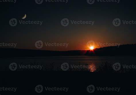 nightfall over a lake with moon and sun 10466833 Stock Photo at Vecteezy