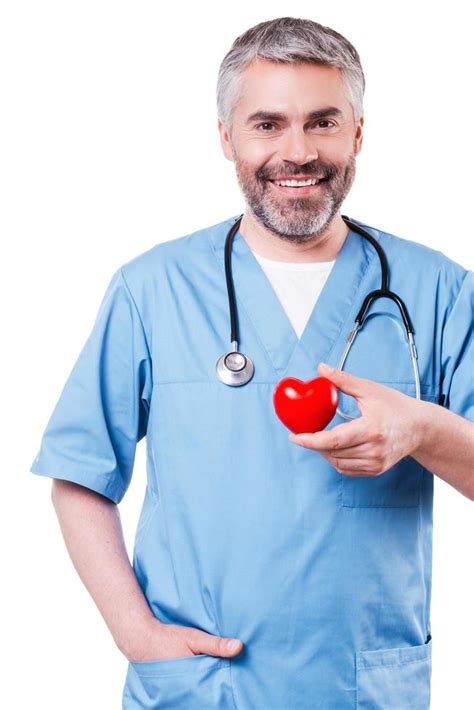 Cardiology surgeon. Confident mature cardiology surgeon holding heart shape toy and smiling ...