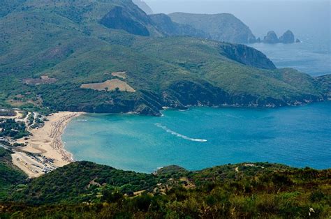 an aerial view of a beach and mountains in the distance, with a boat ...