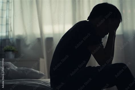 Depressed lonely man sitting alone on the bed with hands on head feel ...