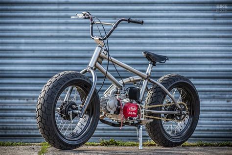 an old style motorcycle parked in front of a garage door with no wheels on it