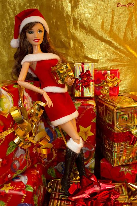 a barbie doll dressed as santa claus with presents on the floor and gold foil background